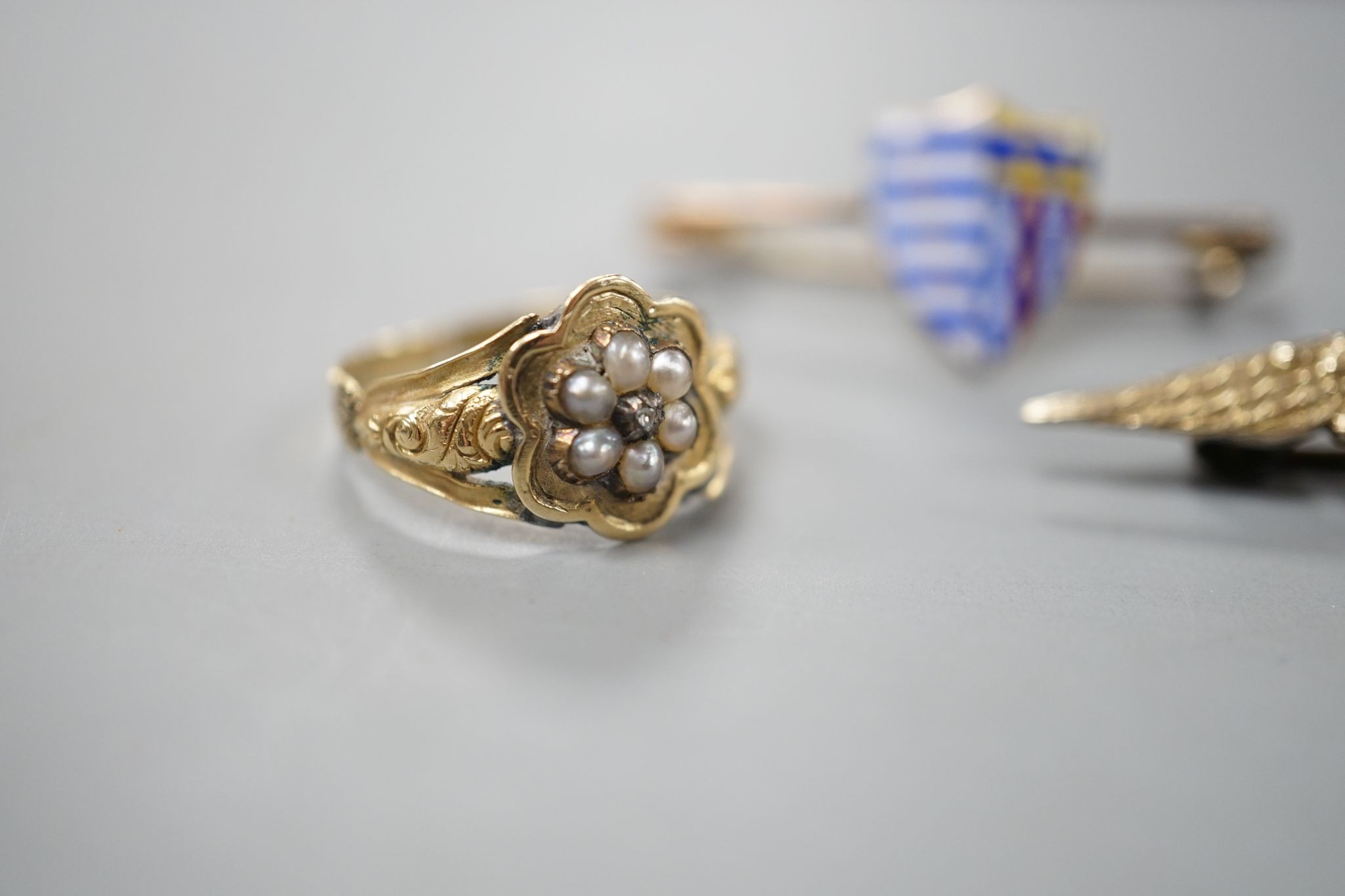 A William IV yellow metal, seed pearl and diamond set mourning ring (a.f.), size K/L and two brooches including 9ct gold and enamel.